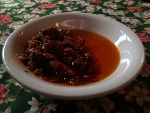 a dish of generous amount of house made sundried tomato and extra virgin olive oil